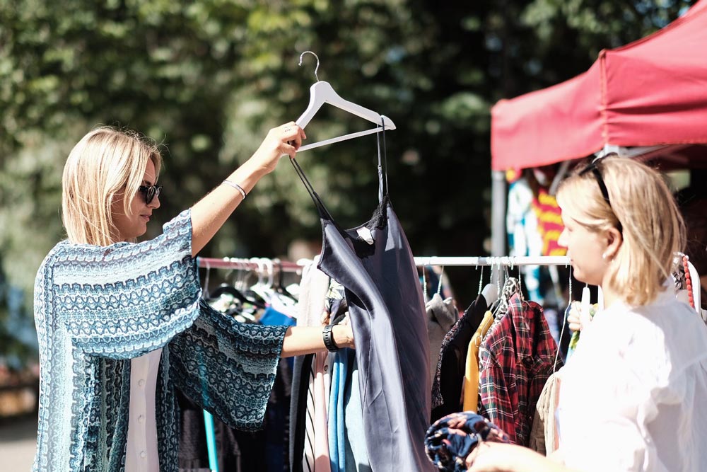Personer som kollar efter kläder i ett loppisstånd på Hornstull marknad